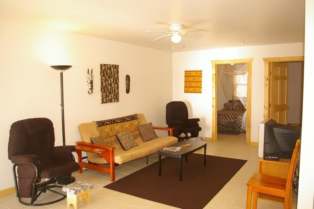 Una sala de estar con un sofá, dos sillones, una mesa de centro y una televisión.