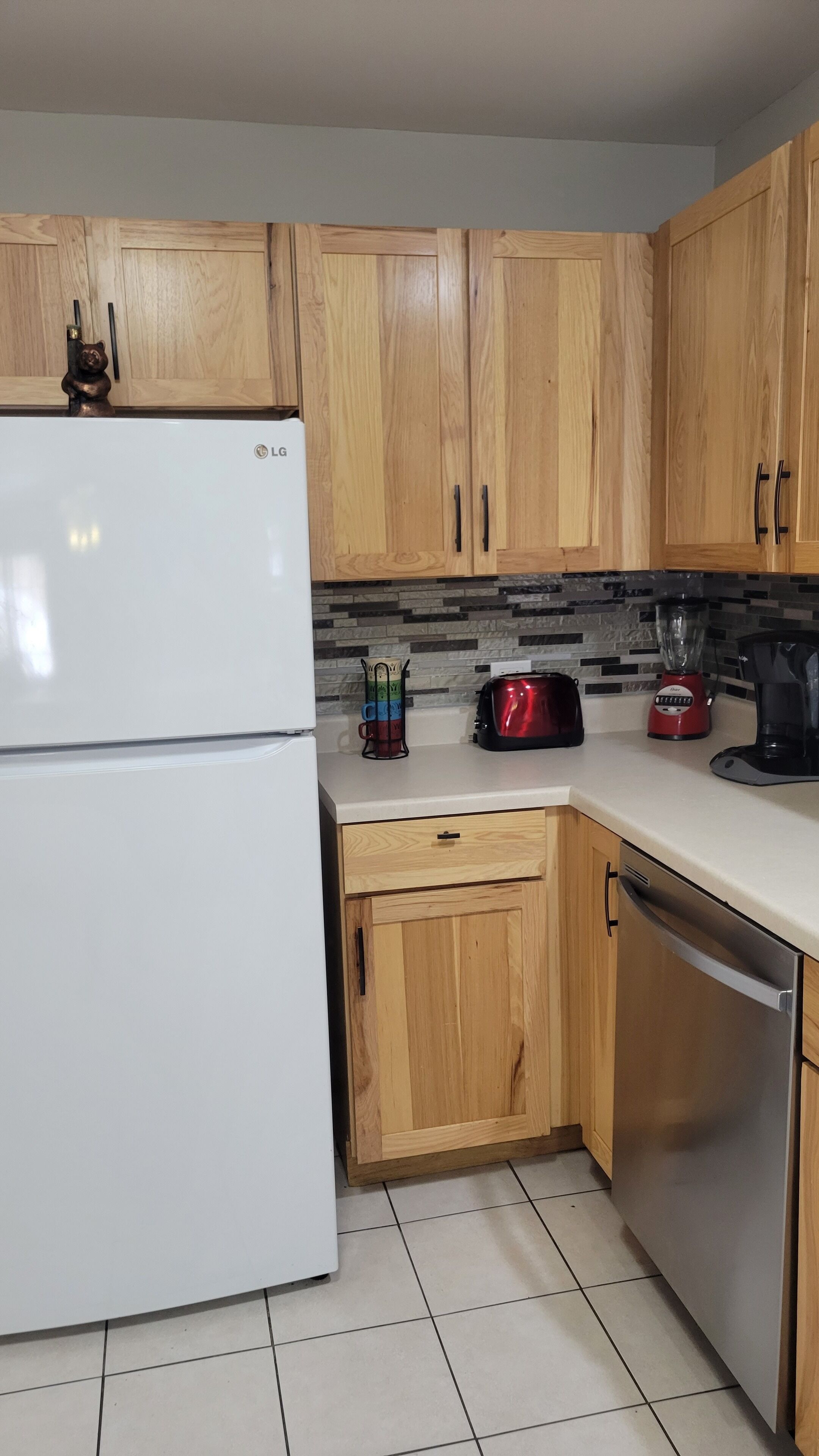 A kitchen with wooden cabinets, a white refrigerator, a toaster, a blender, and a coffee maker.