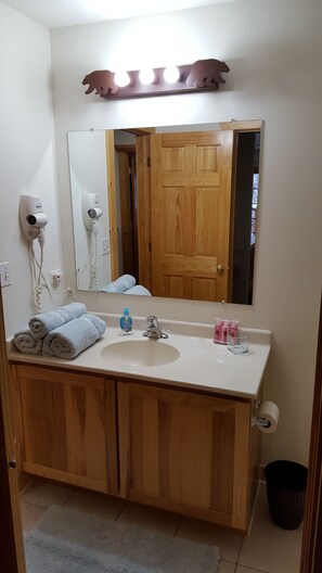 A bathroom with a wooden vanity, a sink, a mirror, and a hairdryer.