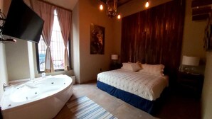 A bedroom with a large bed, a bathtub, and a wooden wall. - Independencia Dos 7 Hotel Boutique (Querétaro)
