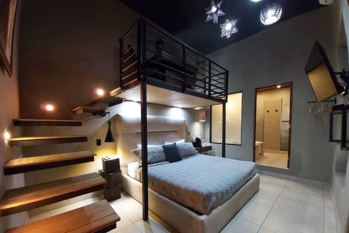 Une chambre moderne avec un lit superposé, un escalier en bois et une mezzanine.