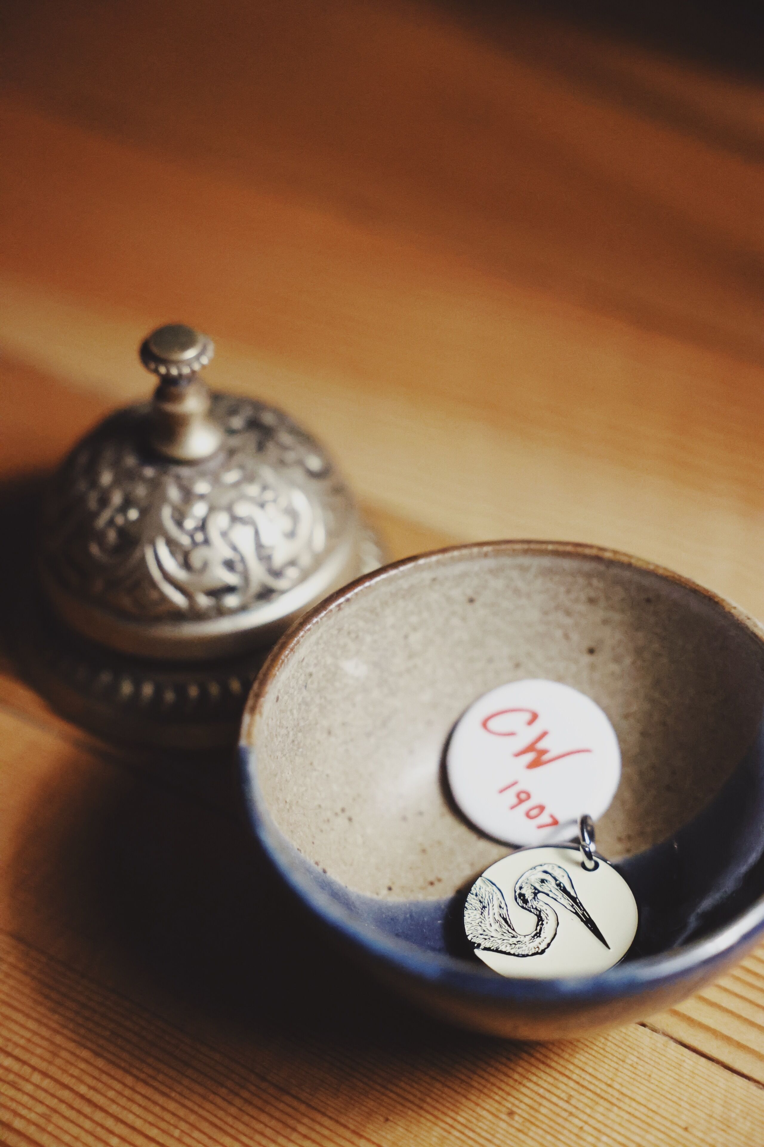 A ceramic bowl with a metal lid and a decorative metal tag.