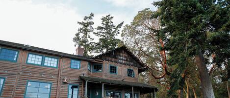 A log cabin with a porch, multiple windows, and a stone foundation.