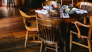 A wooden dining table set with chairs, a bar area with stools, and a green tiled backsplash. - Captain Whidbey (Coupeville)