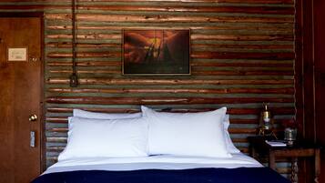 Una habitación estilo cabaña de madera con una cama, un cuadro en la pared y una pequeña mesa con un farol.