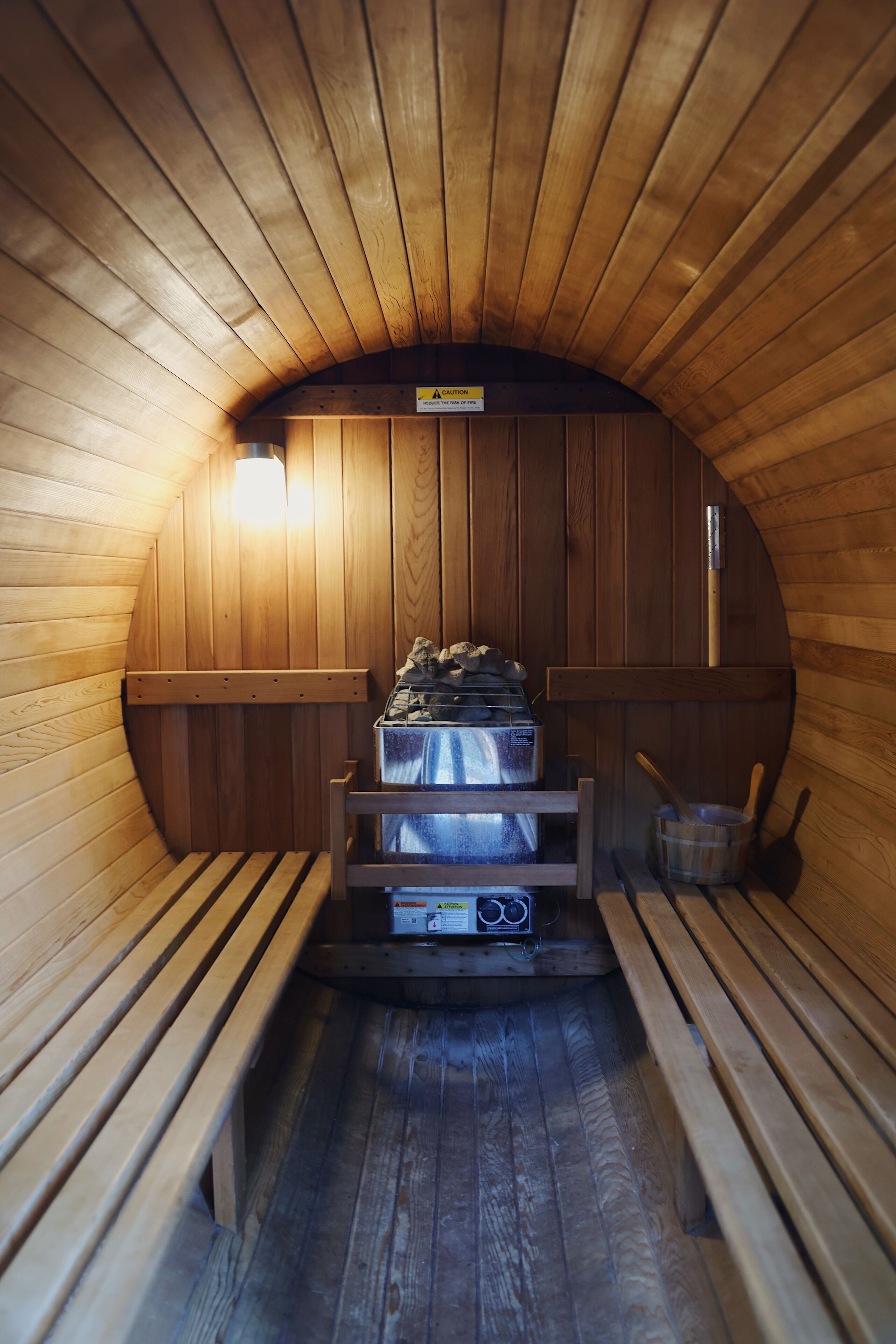 Sauna, jossa on puiset lauteet, lauteiden alla oleva lämmitin ja kiuas.