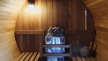 A sauna with wooden benches, a bench heater, and a sauna heater.