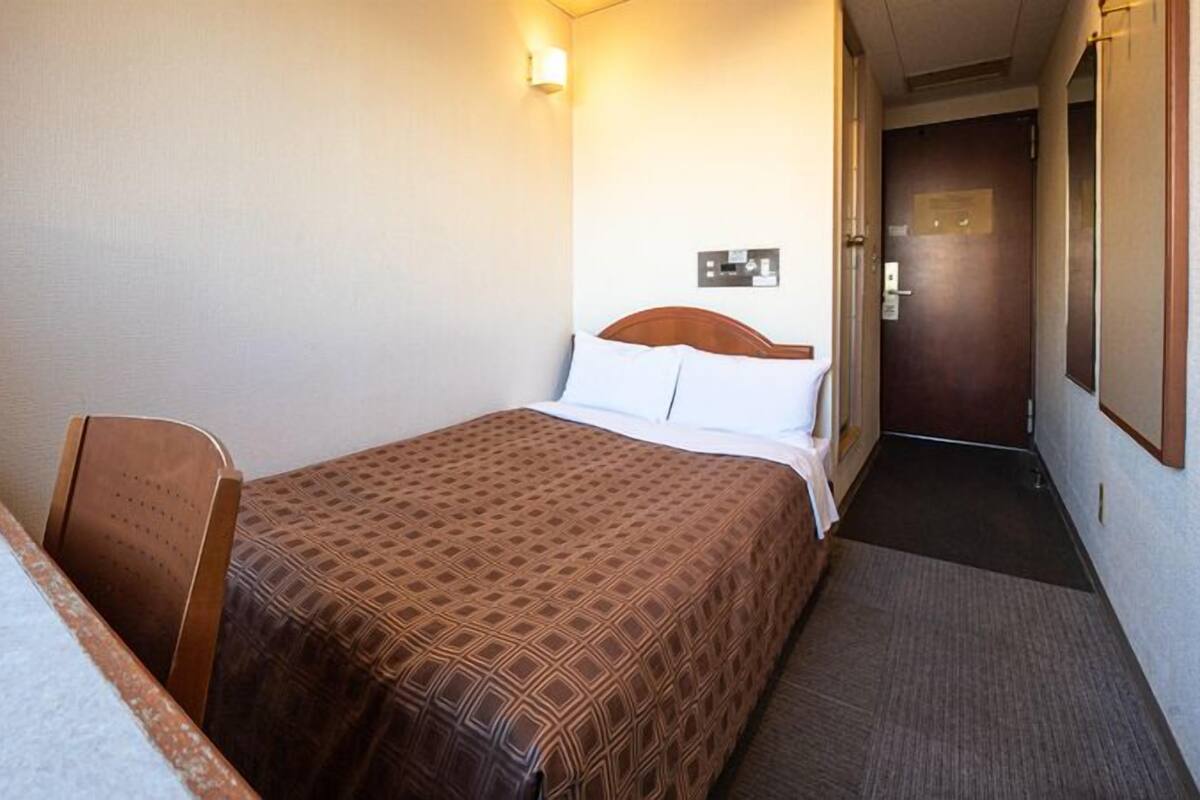A hotel room with a bed, a chair, a desk, and a television.