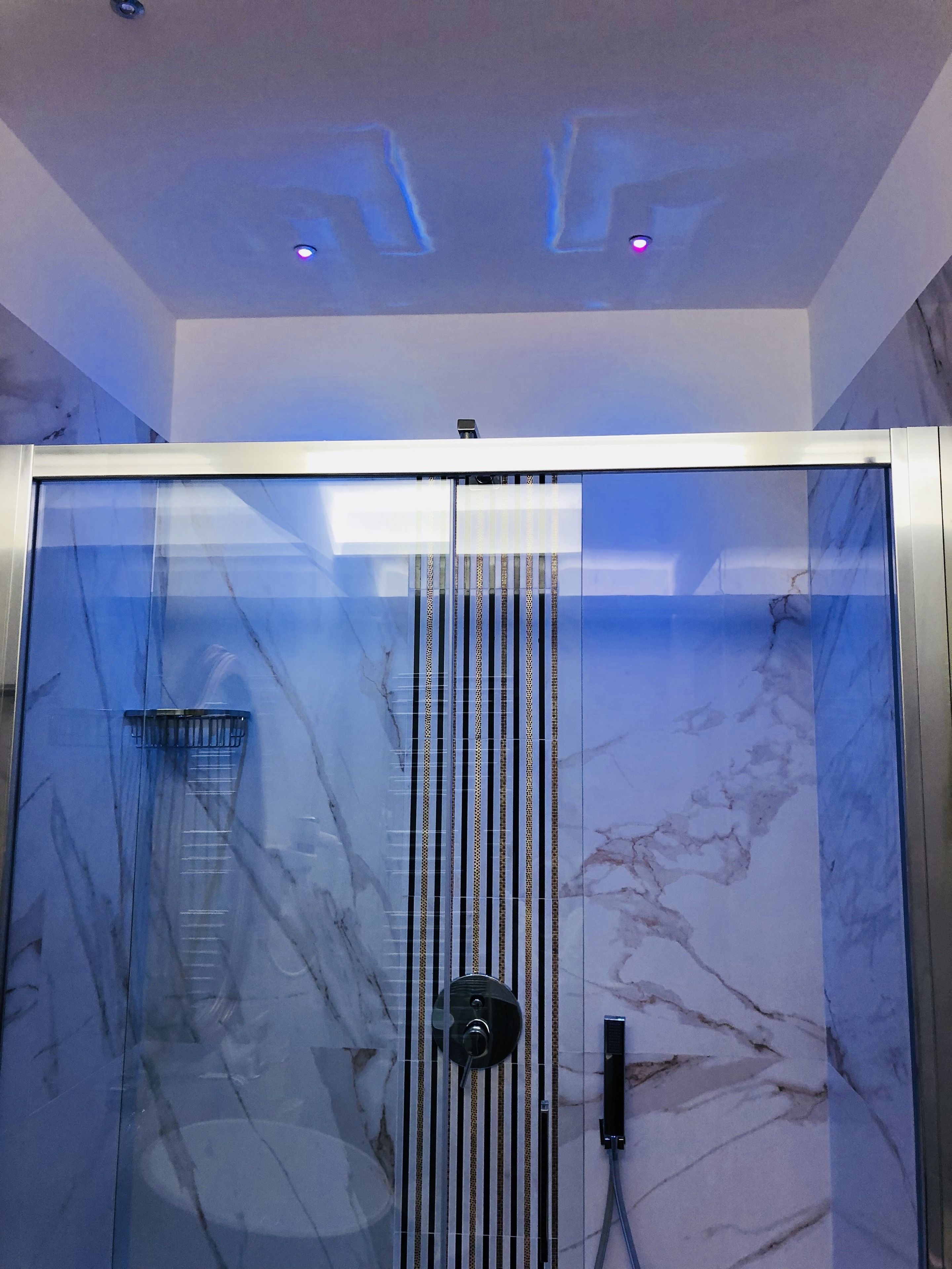 A modern shower enclosure with a glass door, a control panel, and a towel rack.