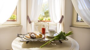 A breakfast table with pastries, a glass of juice, and a tulip. - Trastevere Royal Suite (Rome)