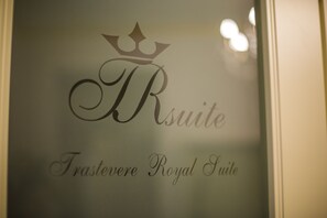 A sign with the text "Trastevere Royal Suite" and a crown symbol above the letter "R". - Trastevere Royal Suite (Rome)