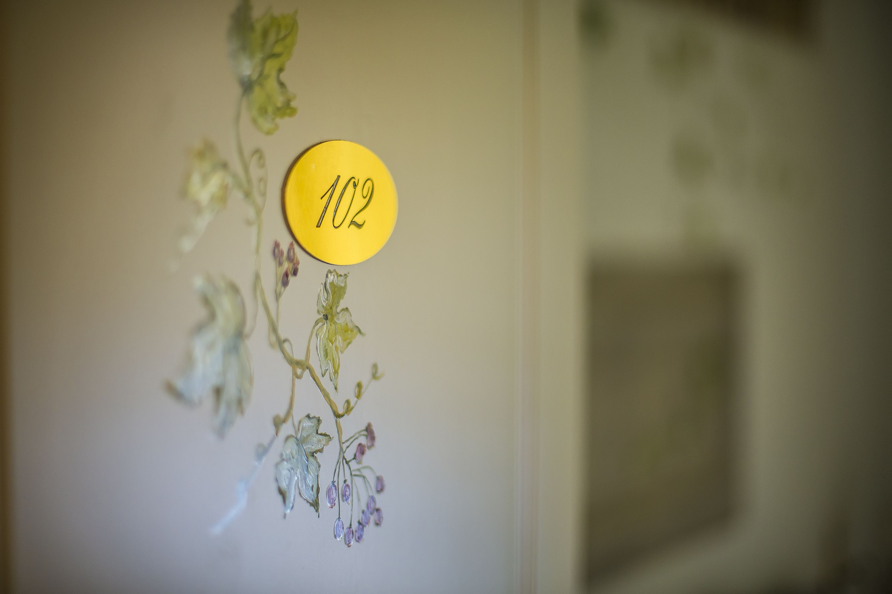 A wall with a yellow sign labeled "102" and a floral decoration.