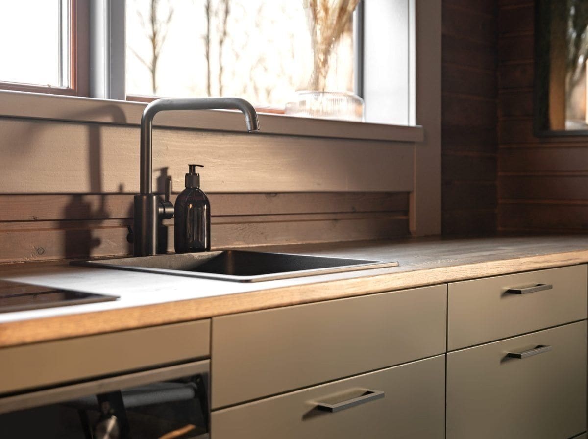 A kitchen with a modern faucet, a sink, and a window with a view of trees.
