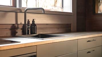 A kitchen with a modern faucet, a sink, and a window with a view of trees.
