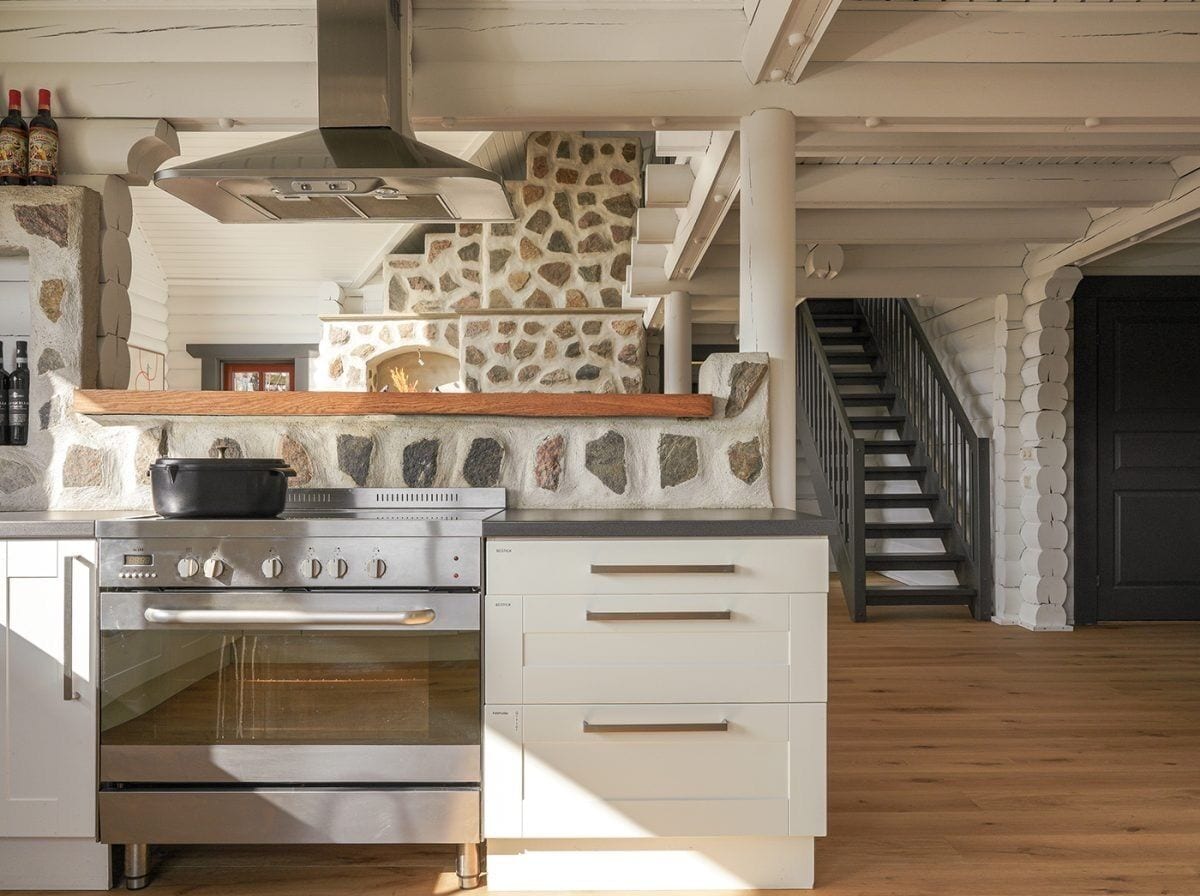 A kitchen with a stone fireplace, a stainless steel oven, and a wooden countertop.