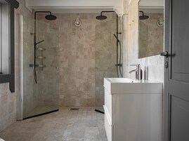 Un baño moderno con ducha envuelta en vidrio, tocador blanco y un espejo grande.