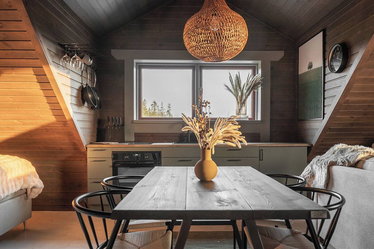 Eine gemütliche Loft-Küche mit Holztisch, Pendelleuchte und Blick ins Freie durch ein großes Fenster.
