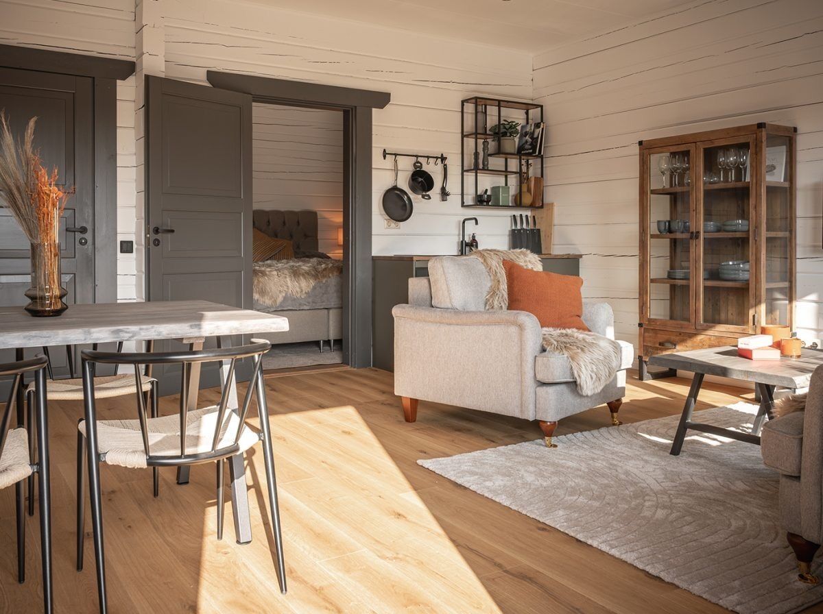 Een gezellige woonkamer met een eethoek, met een bank, stoelen, een salontafel en een kast met glazen deuren.