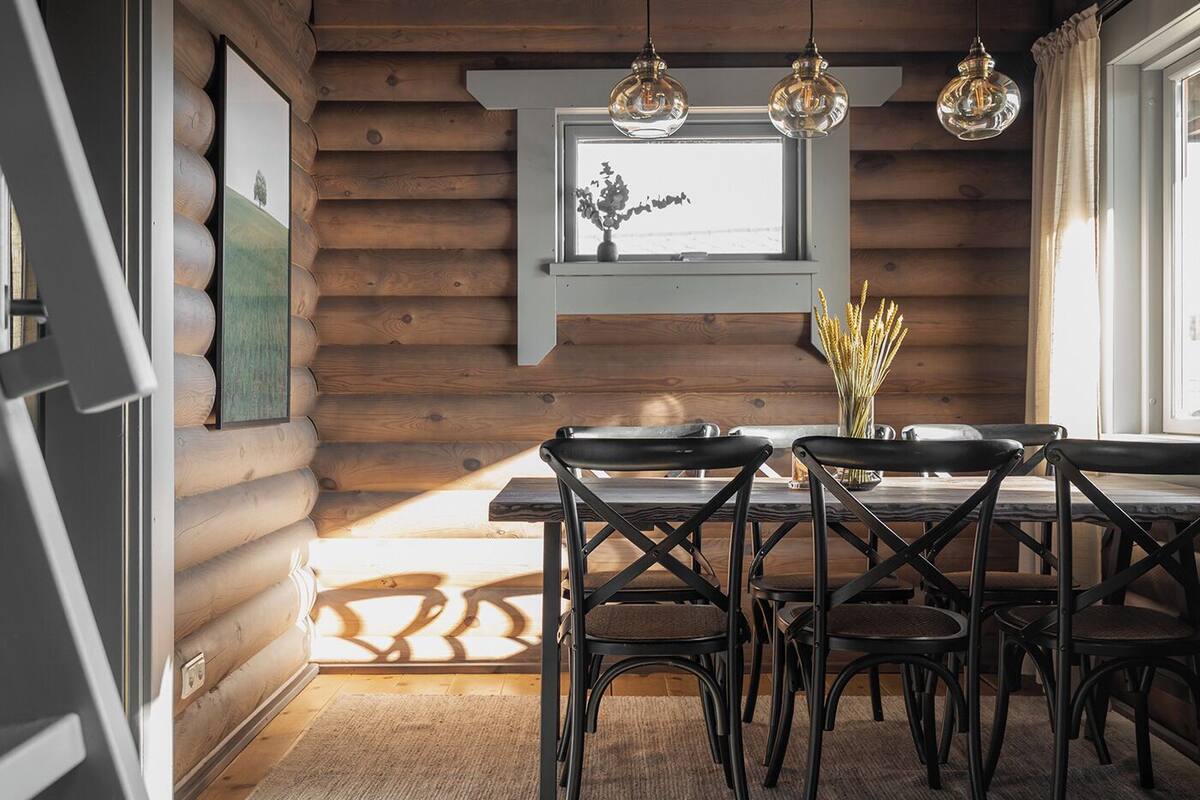 Ein rustikales Holzhaus-Interieur mit Esstisch, Stühlen und Pendelleuchten.
