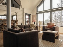 Un salón amplio con un gran ventanal, chimenea y una zona de estar acogedora.