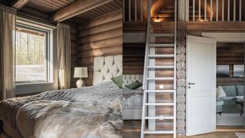 A log cabin bedroom with a bed, a nightstand, a lamp, and a window with curtains.