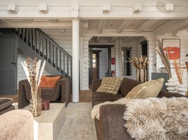 Una sala de estar moderna con una escalera, sofás y elementos decorativos.