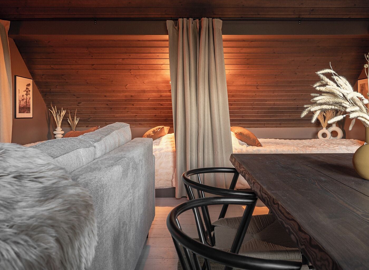 Un dormitorio acogedor con techo de madera, una cama con cubrecama blanco, una mesa de madera y dos sillas.