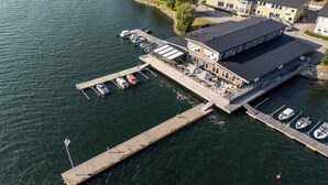 Vista aérea de un hotel frente al mar con un muelle, barcos y un edificio con terraza.