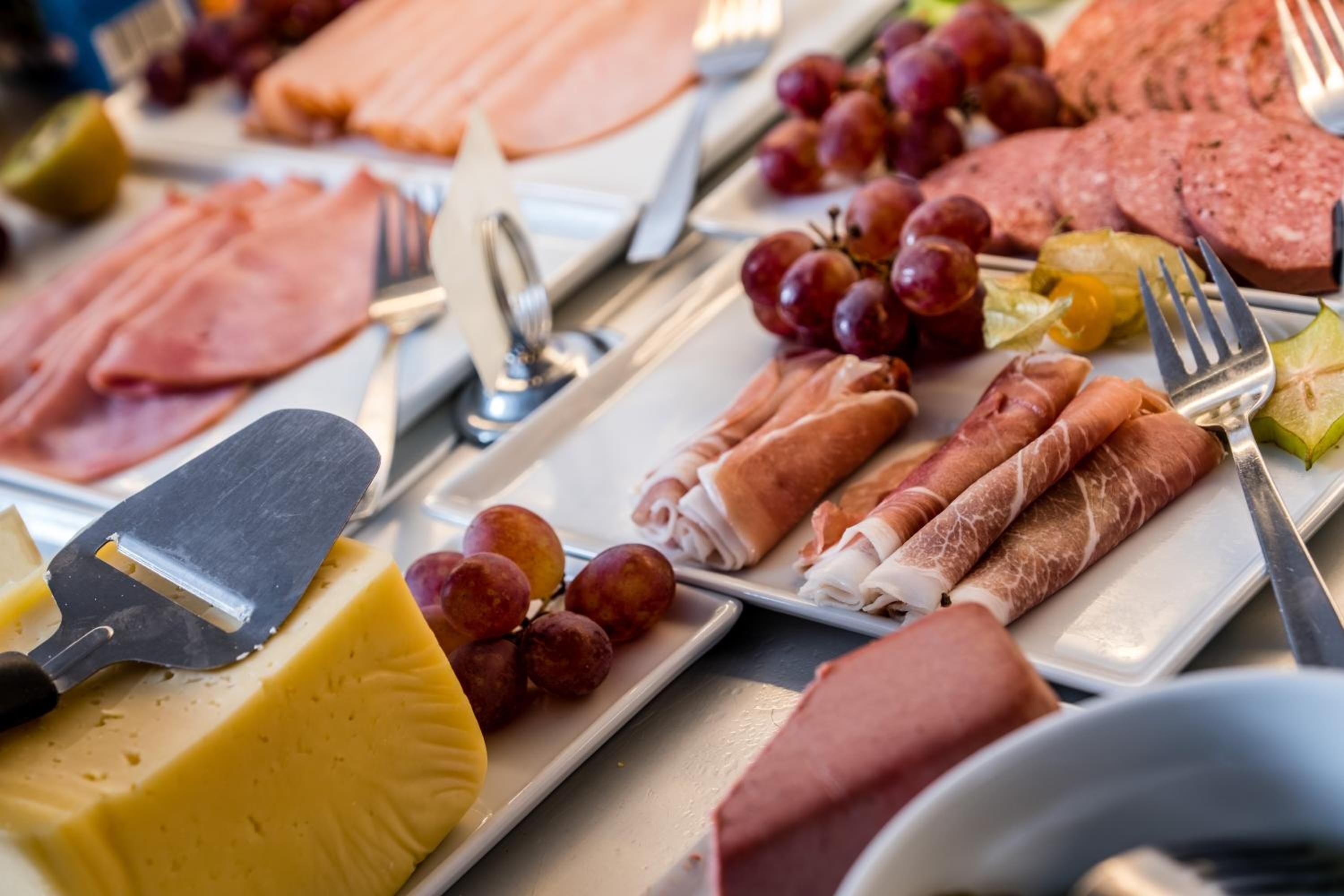 A variety of cheeses, cured meats, and fruits on a serving tray.