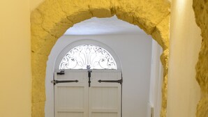 Un couloir avec une porte blanche sous une arche, qui mène à une pièce.