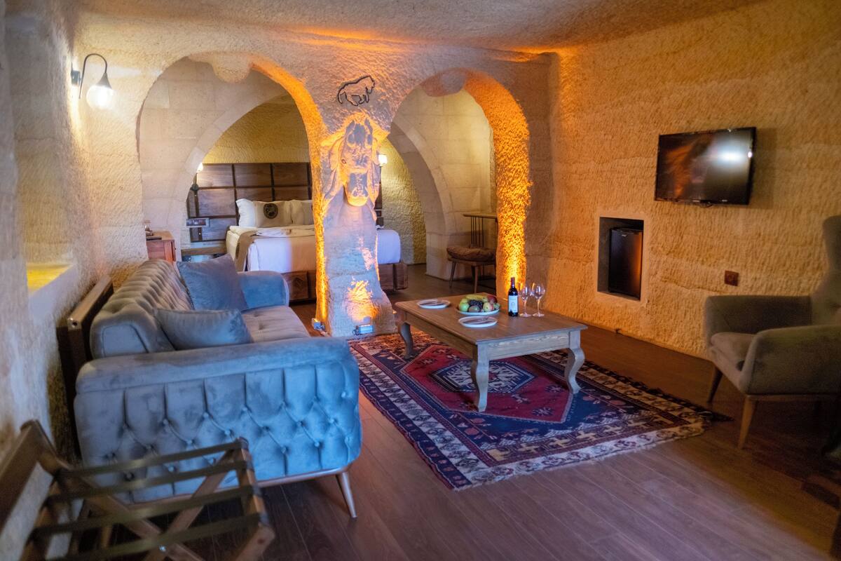 Una sala de estar acogedora con un sofá, sillones, una mesita de centro y un televisor instalado en la pared.