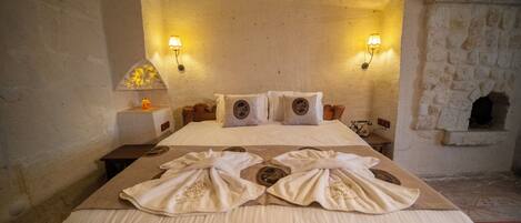 Une chambre d’hôtel avec un grand lit, deux lampes fixées au mur et un mur en pierre décoratif.