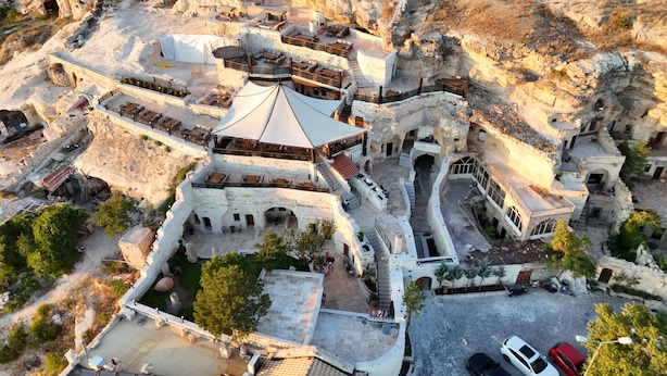 An aerial view of a traditional stone building with multiple levels, outdoor seating areas, and a central courtyard. - Urgup Evi Cave Hotel (Ürgüp)