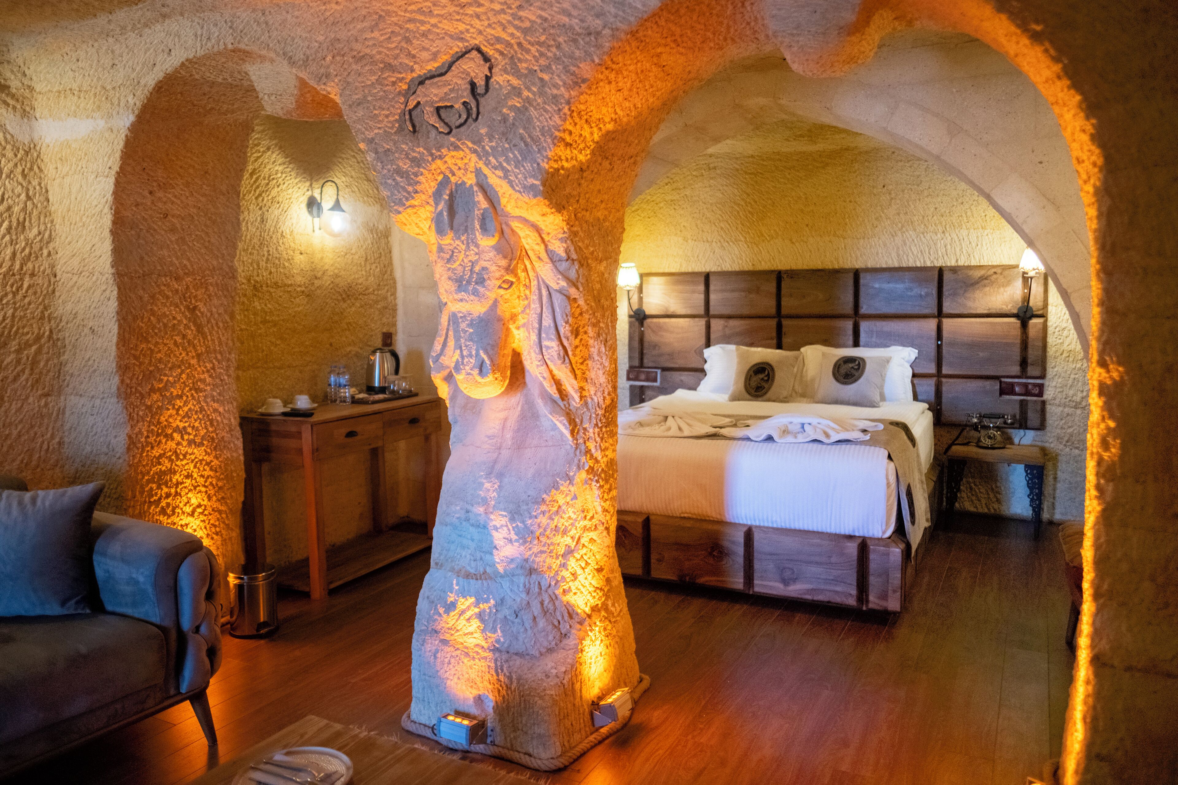 A rustic room with a bed, wooden furniture, and a unique rock sculpture centerpiece.