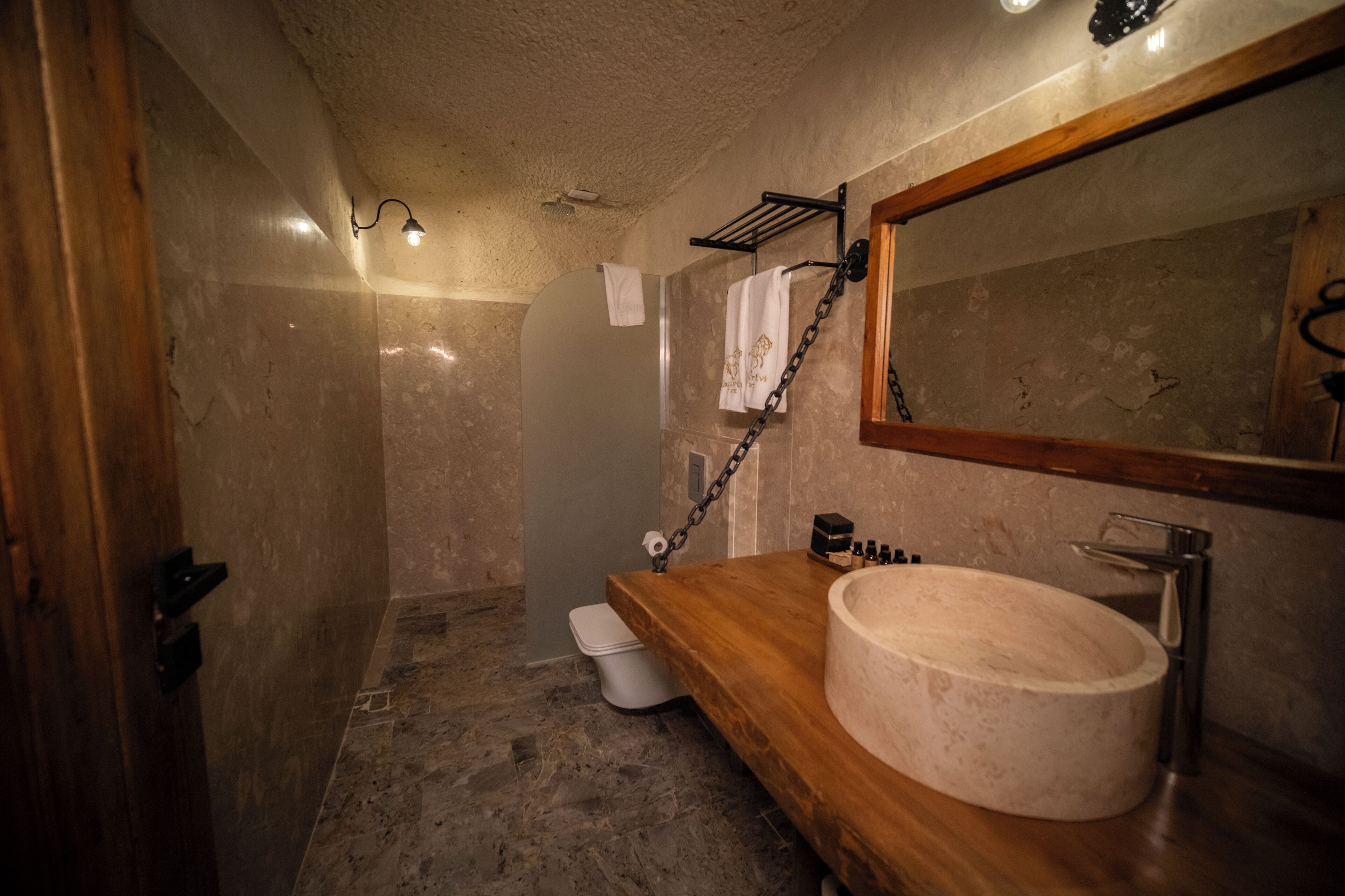A bathroom with a wooden vanity, a large mirror, and a stone sink.