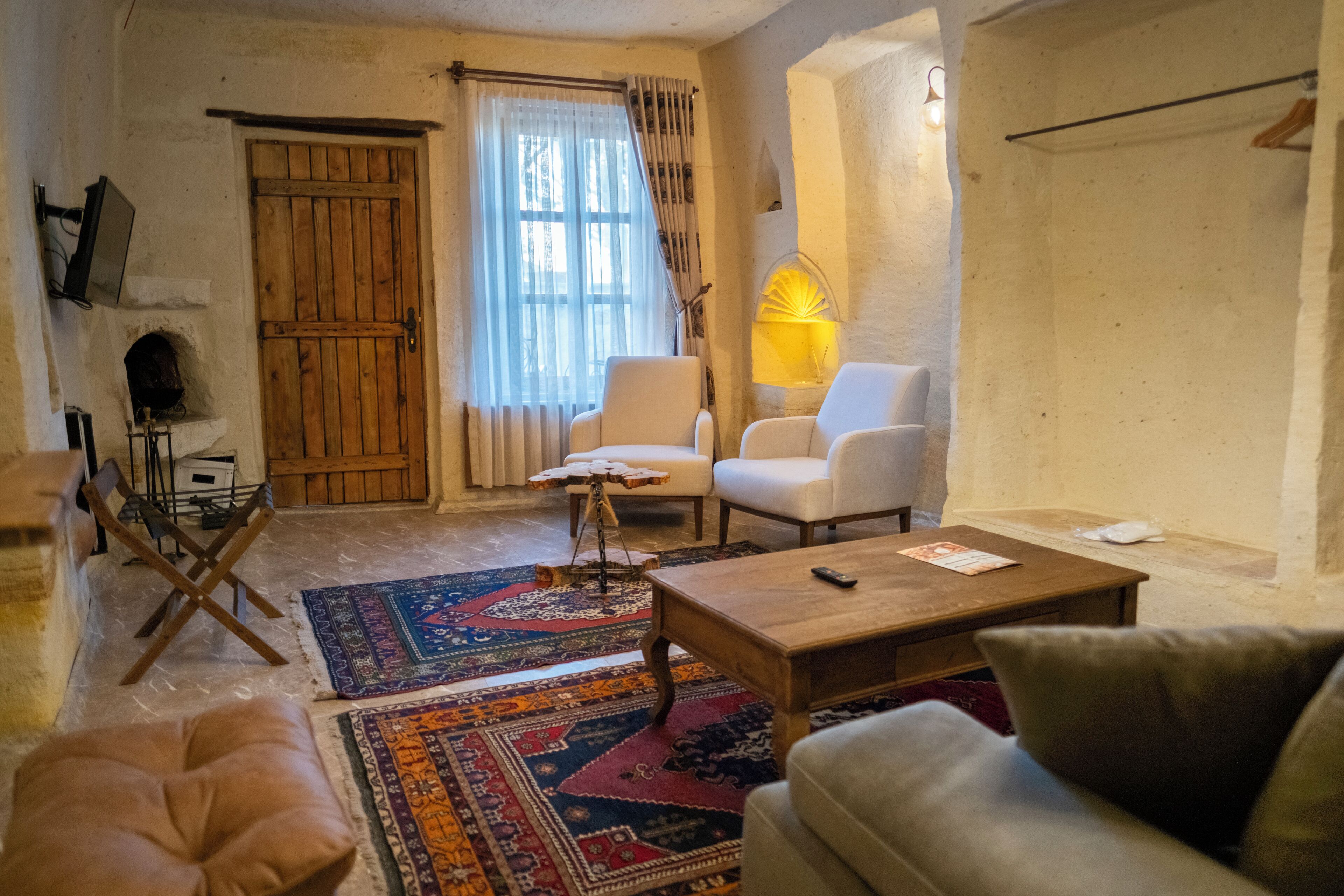 A cozy living room with a fireplace, two armchairs, a coffee table, and a patterned rug.