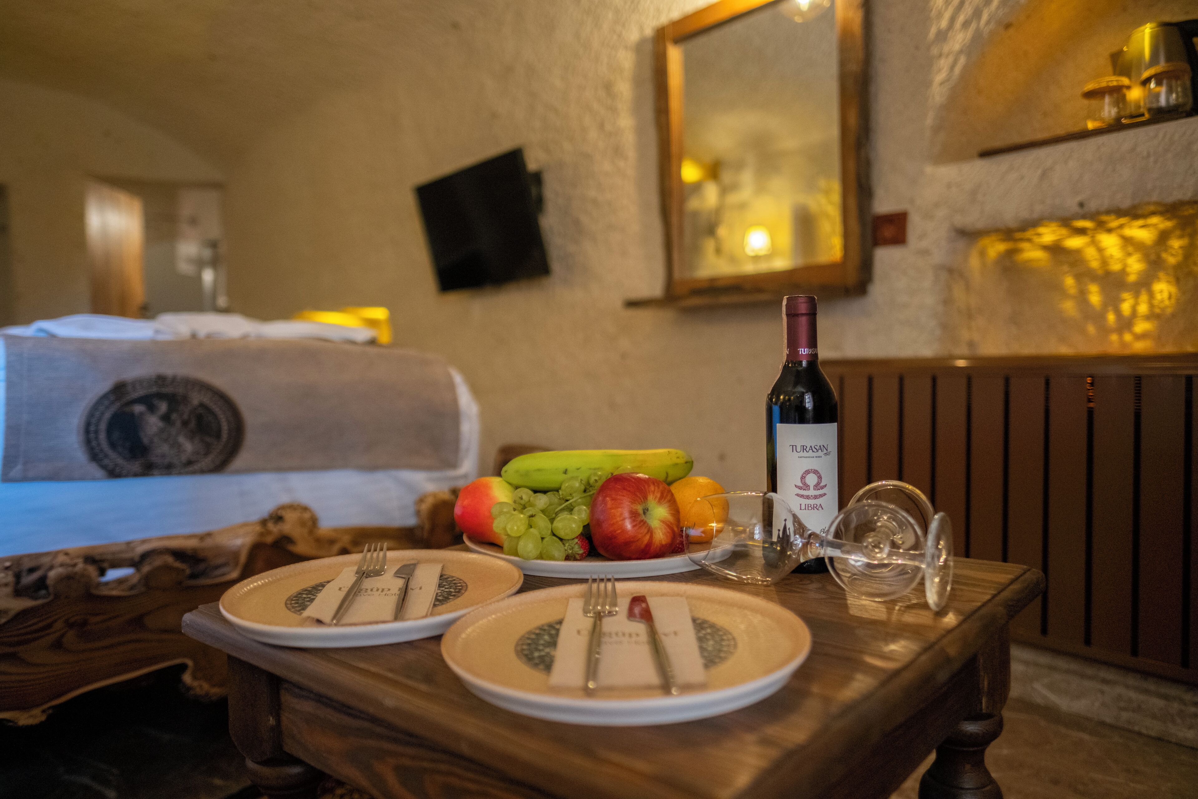 A dining table with plates, cutlery, a bottle of wine, and a glass.