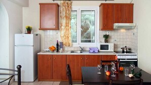 Una cocina compacta con armarios de madera, un refrigerador, un microondas y una estufa.