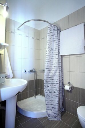 Un baño con ducha, lavamanos e inodoro.