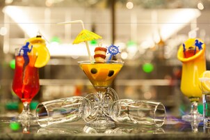Una zona de bar con diferentes vasos de cóctel y algunas botellas vacías sobre la barra.
