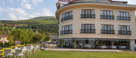 Un hotel con fachada curva, varios balcones y mobiliario para exterior.