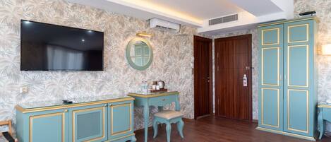 Una habitación con una televisión de pantalla plana, un tocador con espejo, una puerta de madera y un armario color turquesa.