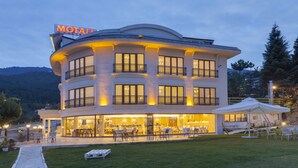A multi-story hotel with a prominent sign, outdoor seating, and a well-lit entrance.