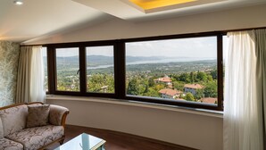 A modern living room with a large window offering a scenic view of a town and mountains.