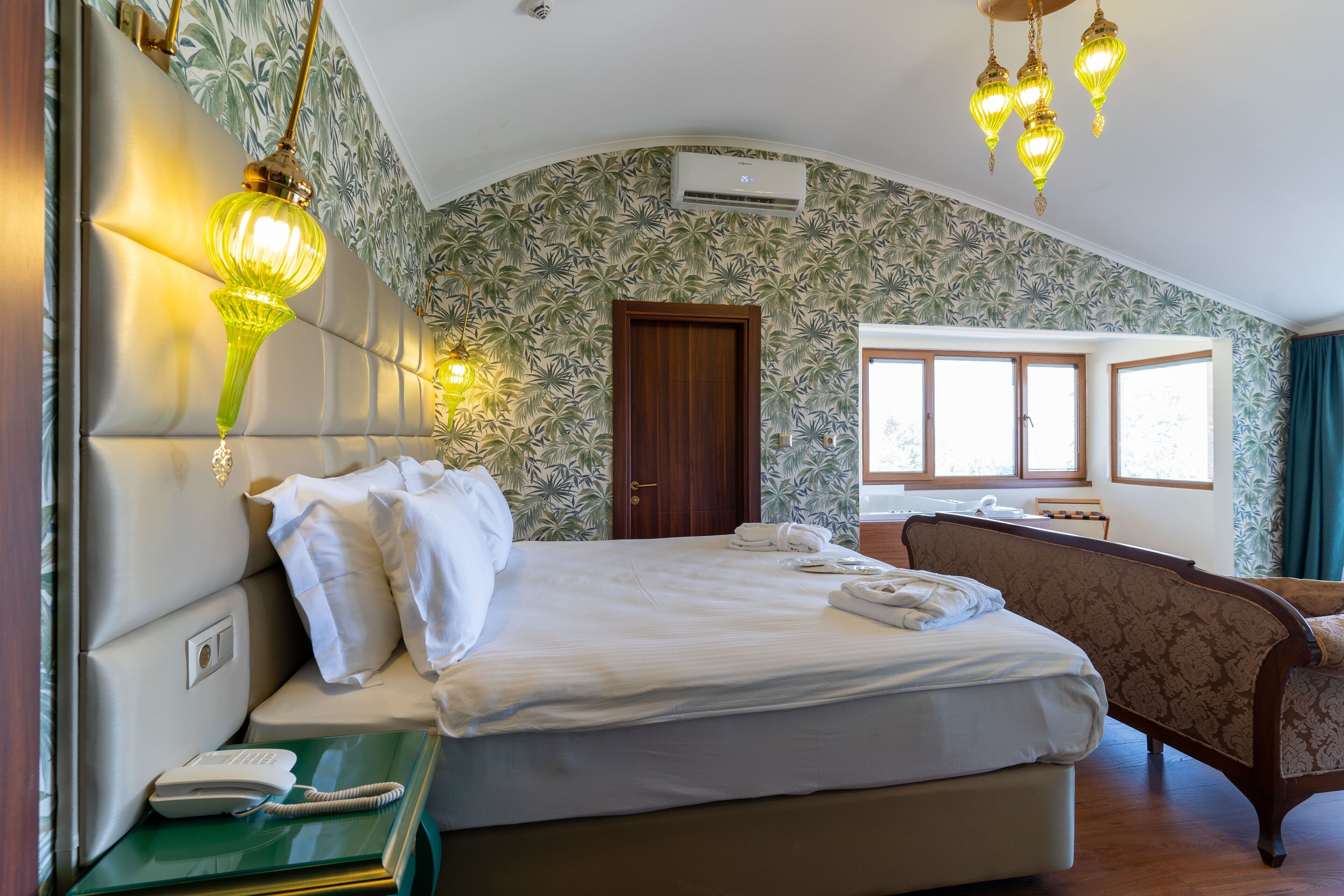 Una habitación de hotel con una cama, una silla, un teléfono y una ventana.