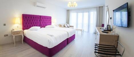 A hotel room with a large bed, a desk, a chair, and a TV.