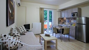A compact living space with a bed, a small table, a kitchenette, and a dining area. - Niriides (Lefkada)