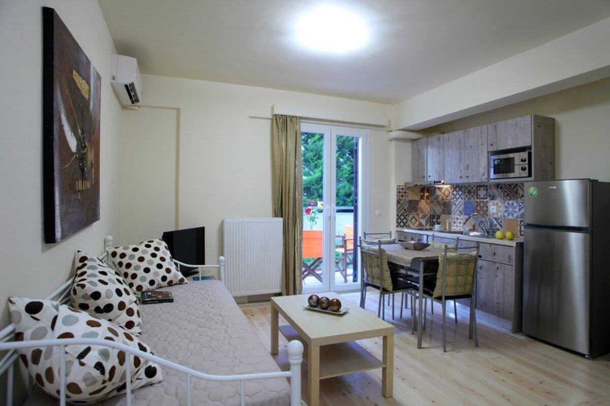 A compact living space with a bed, a small table, a kitchenette, and a dining area.