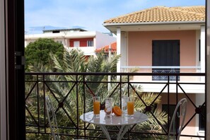 A balcony with a table set for two, featuring two glasses of orange juice and a half-cut orange. - Niriides (Lefkada)