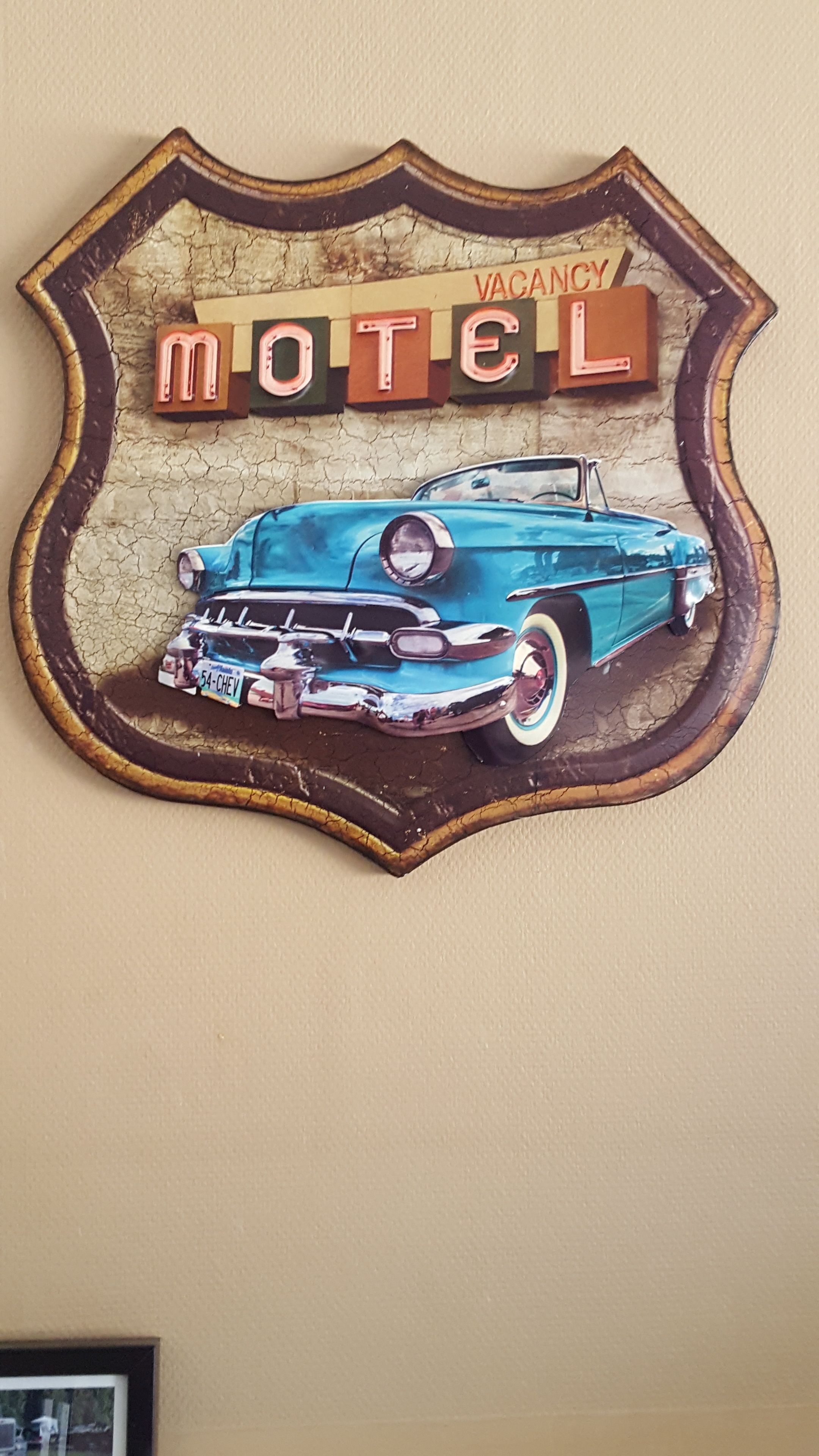 Un cartello da motel vintage con un'illustrazione di un'auto d'epoca e la scritta 'VACANCY MOTEL'.